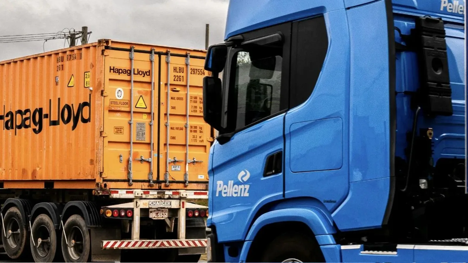 Tractocamión azul remolcando un contenedor de línea naviera sobre carretera